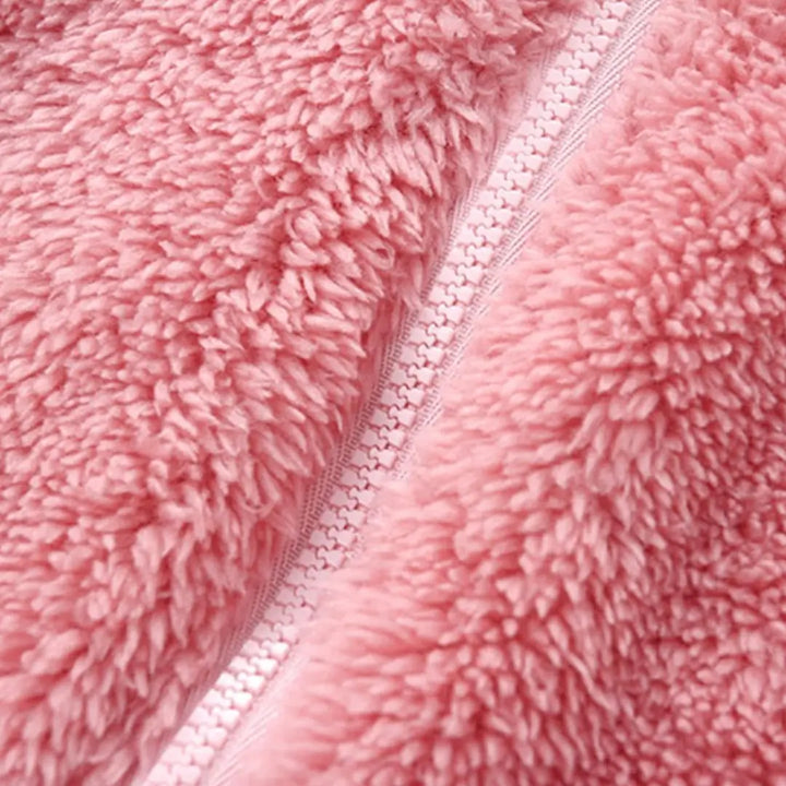 Textura da pelúcia SoftHug™ do macacão Teddy Cozy Rosa Pastel Materna Kid, tecido fofo e quentinho.