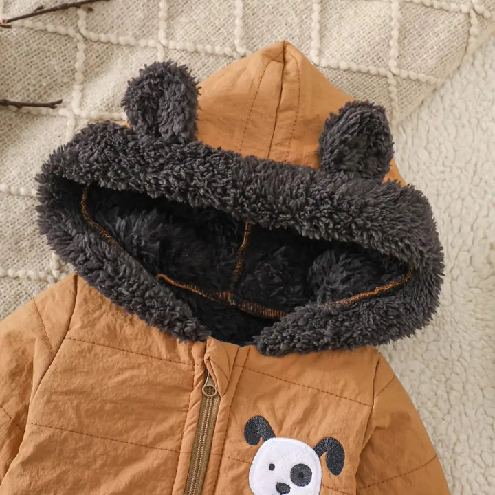 Close do capuz com orelhas e forro sherpa macio do macacão puffer caramelo.