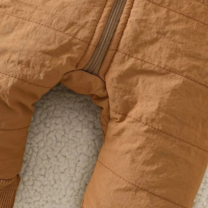 Detalhe do zíper na região da entreperna do macacão puffer caramelo para vestir fácil.