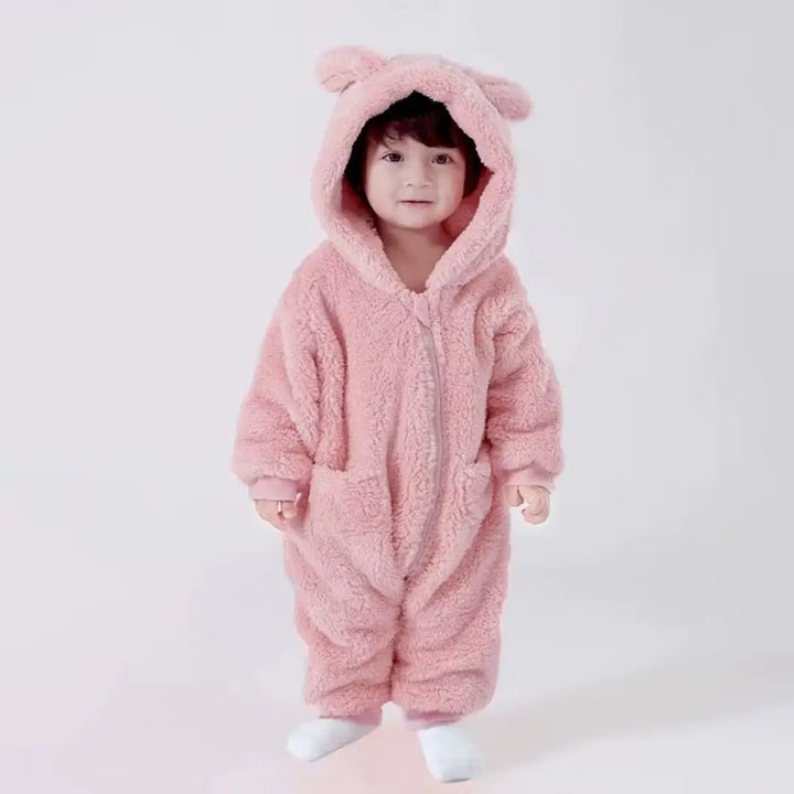 Bebê sorridente com o macacão Teddy Luna Ouro Rosa Materna Kid, pelúcia SoftHug™ aveludada que garante aconchego e estilo