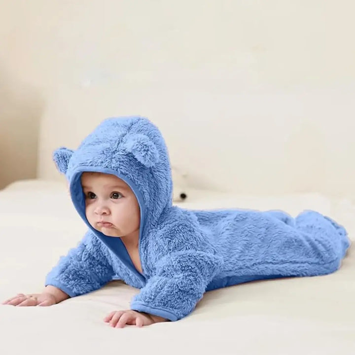 Bebê deitado usando macacão Teddy Sky Azul Celeste Materna Kid, pelúcia aconchegante e toque de ternura.